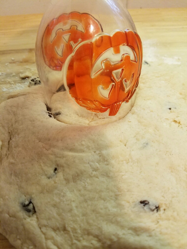 halloween cup being used as biscuit cutter to cut biscuit dough